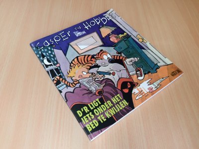 Tweedehands boek: D'r ligt iets onder het bed te wijlen Capser en Hobbes van auteur Bill Watterson - Paperback met rechte rug. Hele lichte gebruikerssporen randen kaft. Binnenin onbeschreven en schoon. In zeer goede conditie.