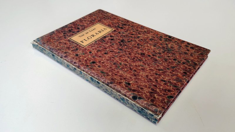 Tweedehands boek: Floraria van auteur Ton de Laat - Hardcover, bovenaan de rug laat het iets los. Pagina's zijn netjes en onbeschreven. In redelijke tot goede staat